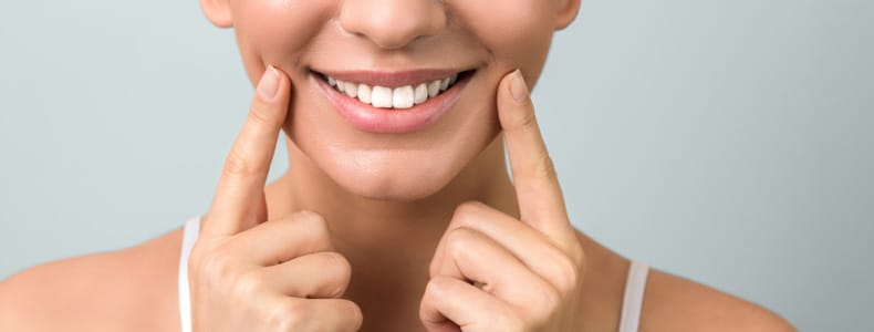 12 Soruda Zirkonyum Diş Kaplama Fiyatları ve Tedavisi 4 Zirkonyum diş kaplama bulunur eli ile dişlerini gösteren kadının ağzında.